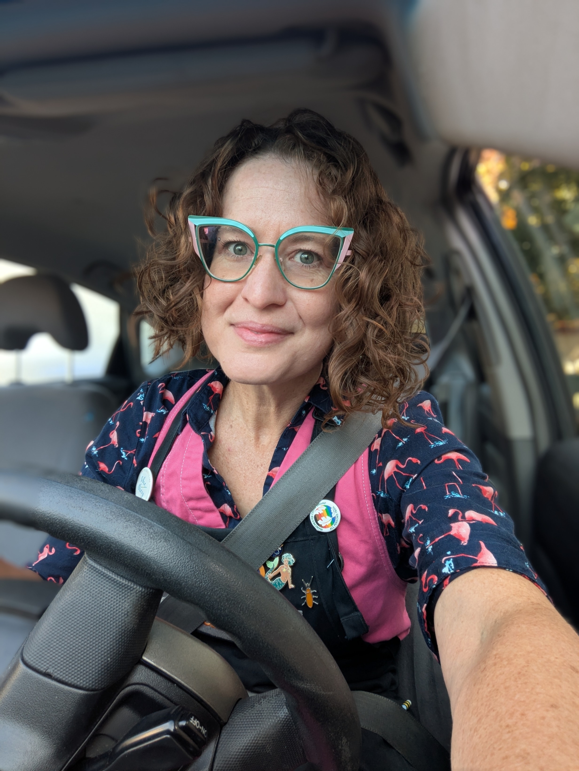 A photo of Amber Nicole. She is centered and directly looking at the camera. Her hair is done up like I love Lucy with a rainbow scarf. Her makeup may be from the 40s. She is colorful and confident. 